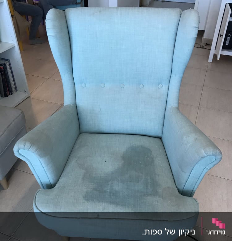 כורסה כחולה עם כתמי מים וצינור ניקוי על הרצפה